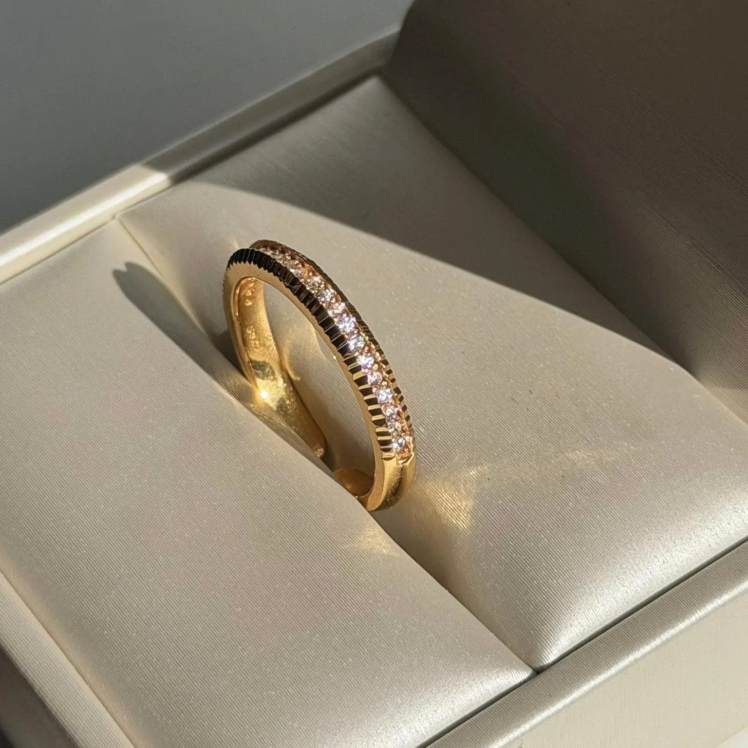 De Fluted Pavé Ring in een geopend sieradendoosje, in het zonlicht