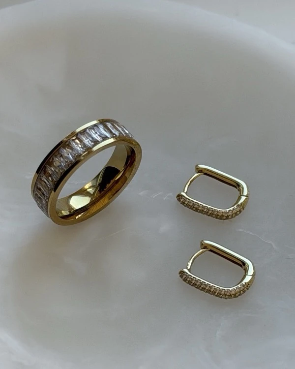 Gouden Eternity Ring en Capsule Pavé Huggies op een marmeren schaal