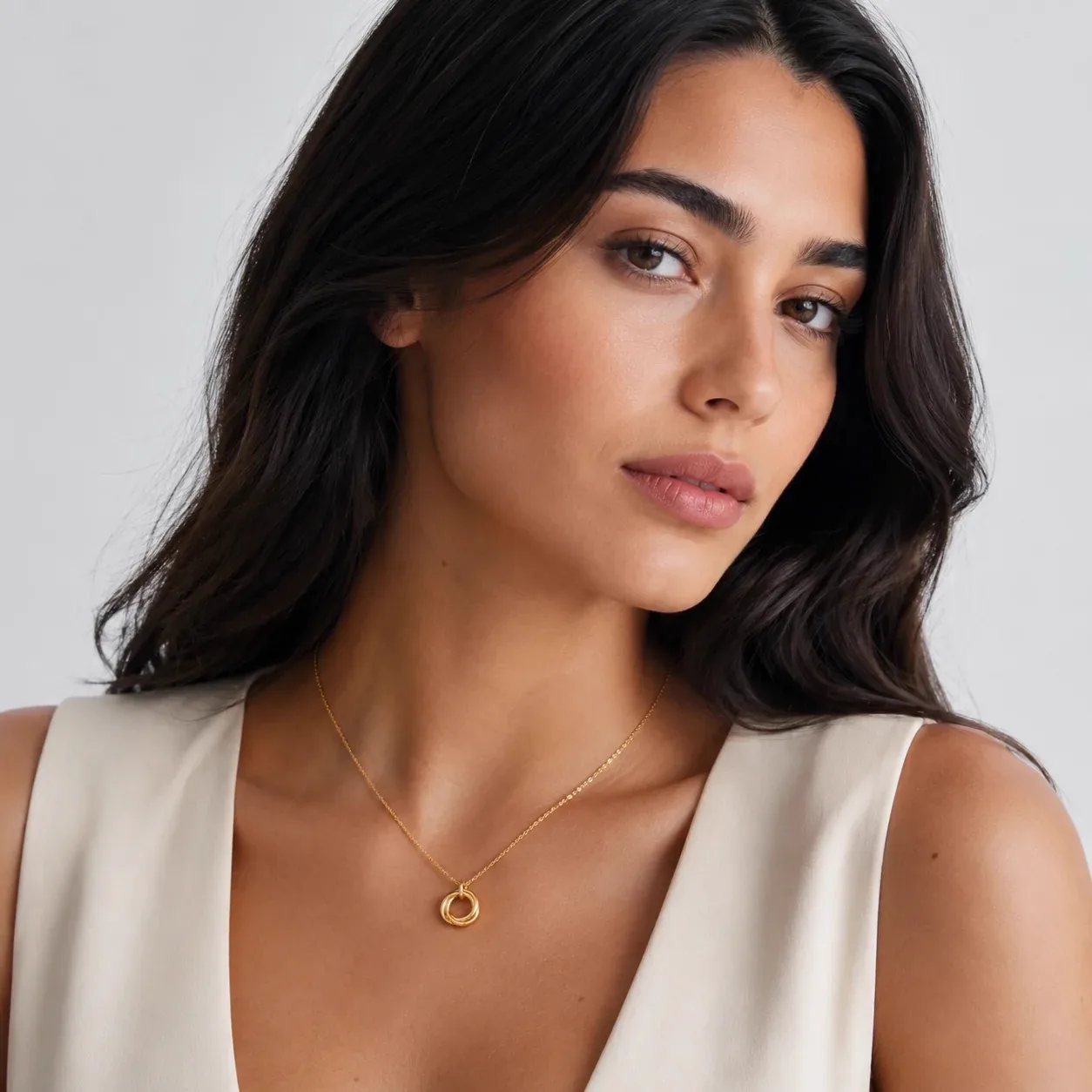 Model draagt een fijne gouden ketting met verstrengelde-ringhanger
