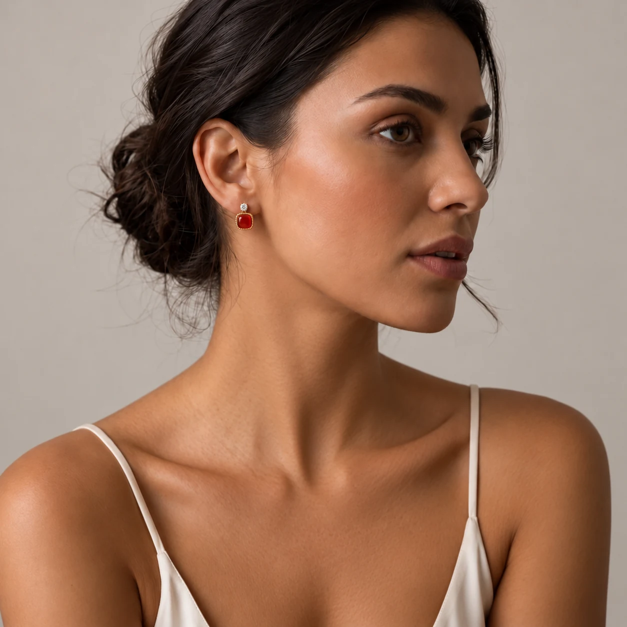 Model draagt de Agate Cushion Studs: rode agaat in een gouden gekartelde zetting
