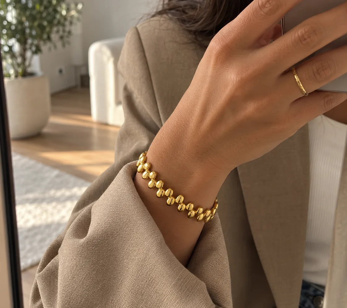 Model draagt de Pebble Row Bangle om de pols, bij een beige blazer