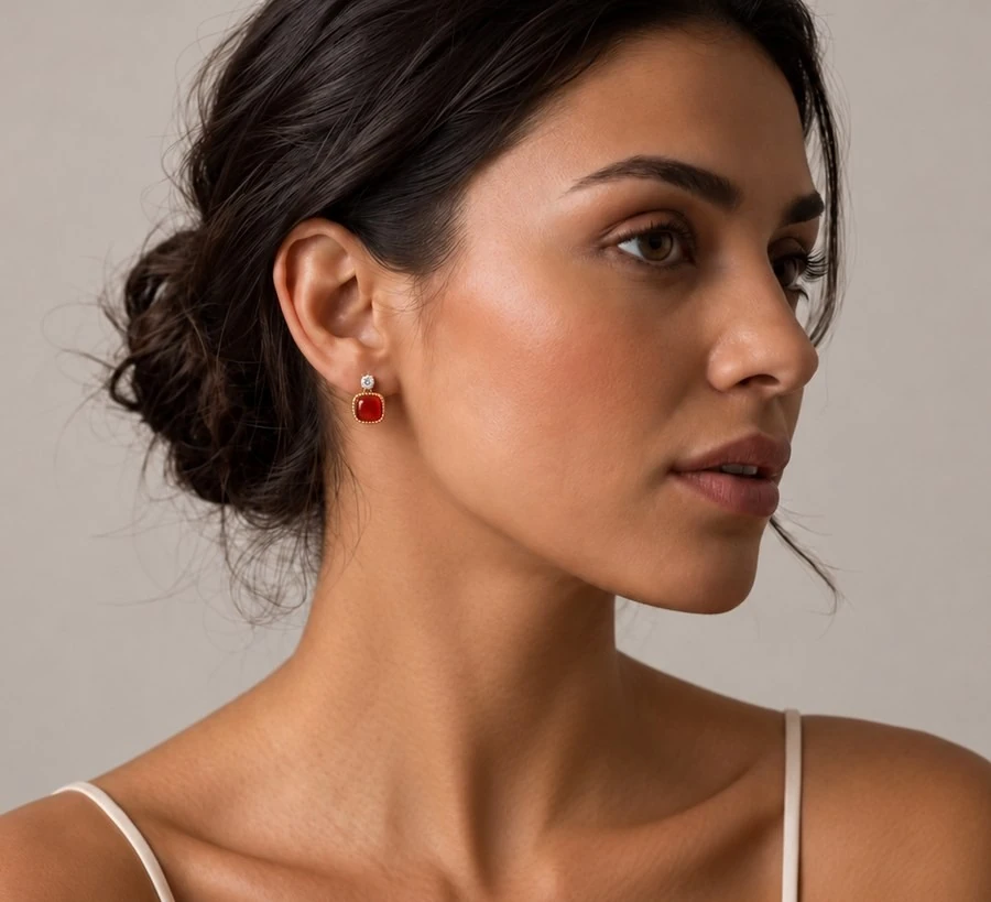 Model draagt sterling zilveren oorbel met rode steen, close-up